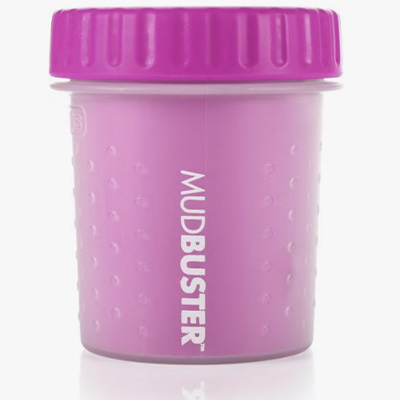  A pink Dexas MudBuster portable dog paw cleaner with a screw-on lid and textured exterior for grip. The word “MUDBUSTER” is printed vertically on the side, showcasing the compact, travel-friendly design for cleaning muddy paws.