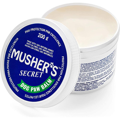 Musher's Secret Dog Paw Wax Open 200g container of Musher’s Secret Dog Paw Balm with a blue lid labeled “Paw Protection Par Excellence.” The label notes it's made with 100% natural waxes and provides protection for dog paws; ingredients and usage instructions are printed on the side.